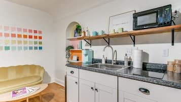 A modern kitchen with white cabinets, a granite countertop, a built-in microwave, and a sink.