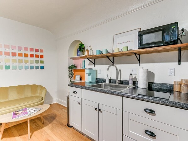 A modern kitchen with white cabinets, a granite countertop, a built-in microwave, and a sink.