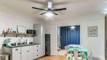 A compact kitchen with a microwave, refrigerator, and a dining area with a table and chairs.