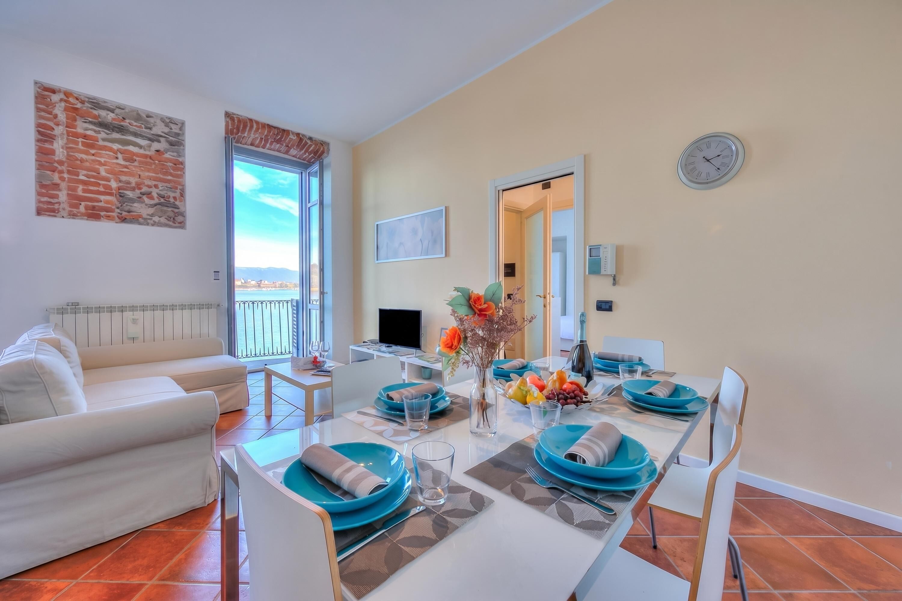 A dining area with a table set for four, a sofa, a TV, and a view of the outdoors.