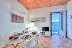 A dining area with a table set for two, a TV, and a view of the sea. - Aparthotel Arona (Arona)