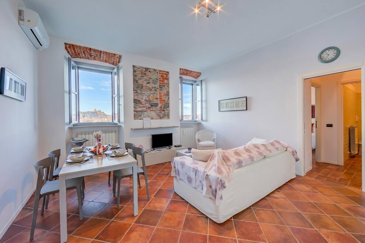 A compact living space with a dining area, a sofa, a TV, and a view through the windows.