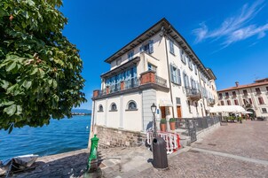 A waterfront building with a balcony, a stone wall, and a clear view of the water.