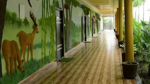 Un pasillo con un mural de ciervos y bambú, puertas y plantas en macetas.