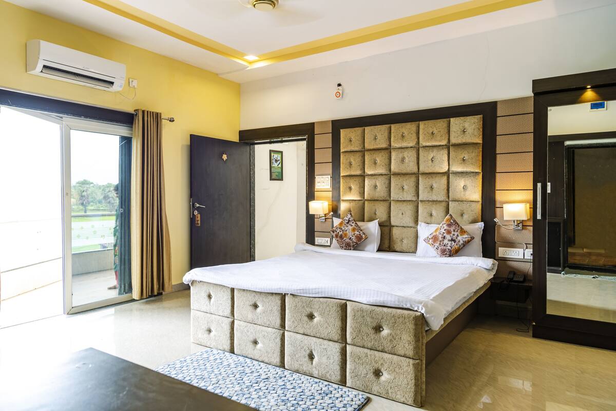 Une chambre d’hôtel avec un grand lit, une tête de lit en bois, une table de chevet et une petite table de nuit avec une lampe.