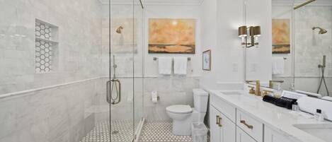 Een moderne badkamer met een douchecabine van glas, een toilet en een wastafel met spiegel.