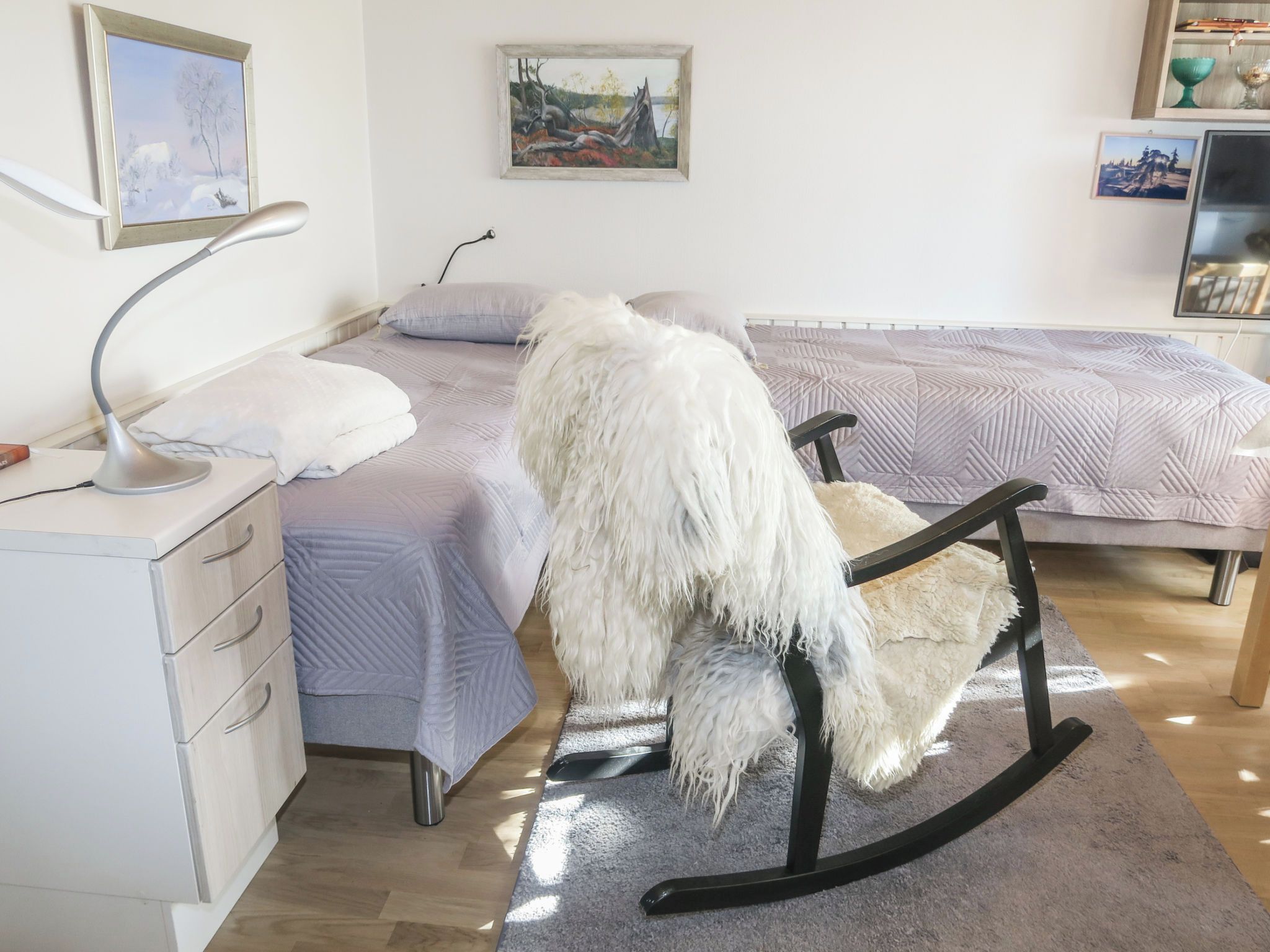 A bedroom with a bed, a chair, a desk, and a lamp.