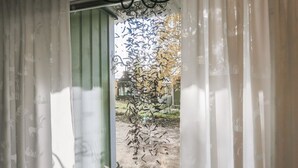 Una ventana con vistas a un jardín, cortinas y una estructura metálica en el exterior.