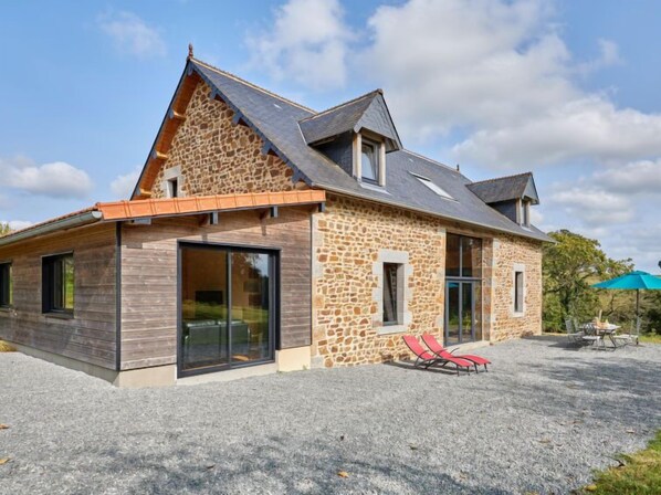 A stone house with a sloped roof, large windows, and a gravel driveway. - La Favrais by Interhome (Saint aubin de terregatte)