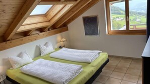 A room with two beds, a skylight, a window with a view, and a chalkboard on the wall. - Penthouse Brugg by Interhome (Amden)