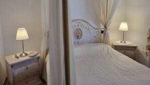 A bedroom with a canopy bed, two bedside tables with lamps, a dresser, and a decorative mirror. - La Vigna di Ranco Ltd N3352 (Paglieta)