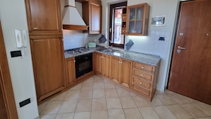 A kitchen with wooden cabinets, a gas stove, a built-in oven, and a tiled backsplash. - La Vigna di Ranco Ltd N3352 (Paglieta)