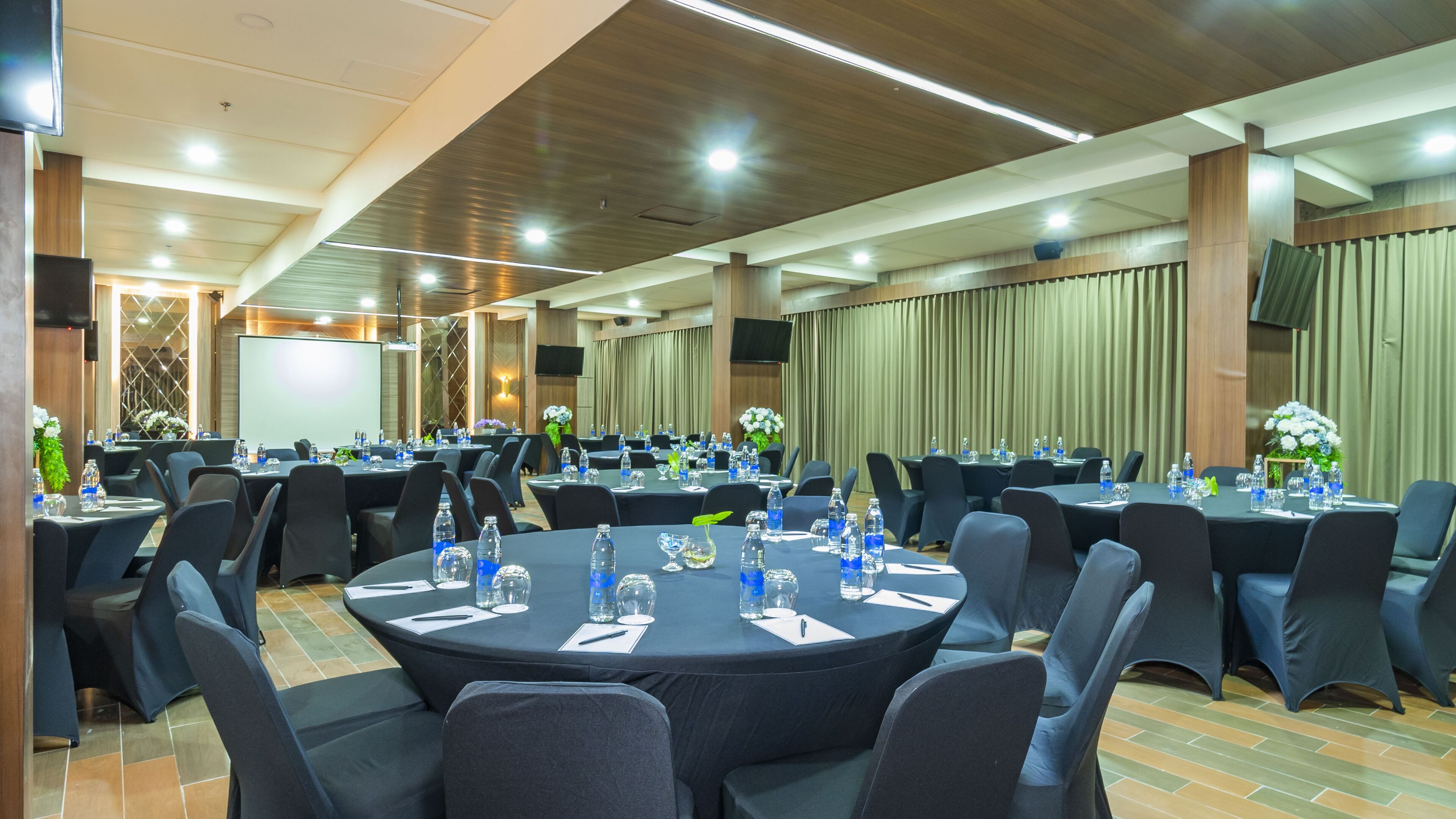 A conference room with round tables, chairs, and water bottles.