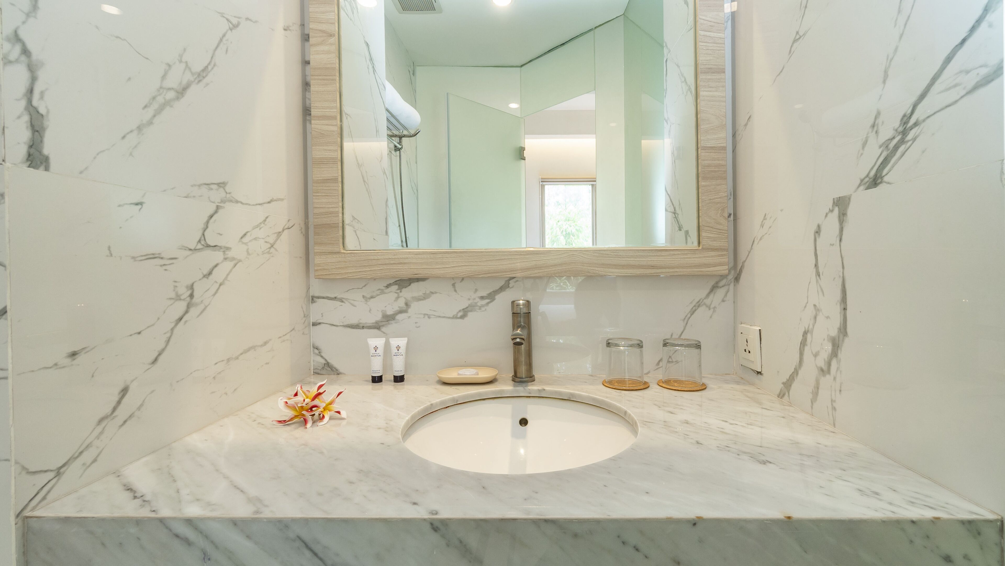 A bathroom with a marble sink, a large mirror, and toiletries on the counter.
