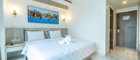 Una habitación de hotel con una cama grande, un cuadro en la pared y una puerta a la derecha.
