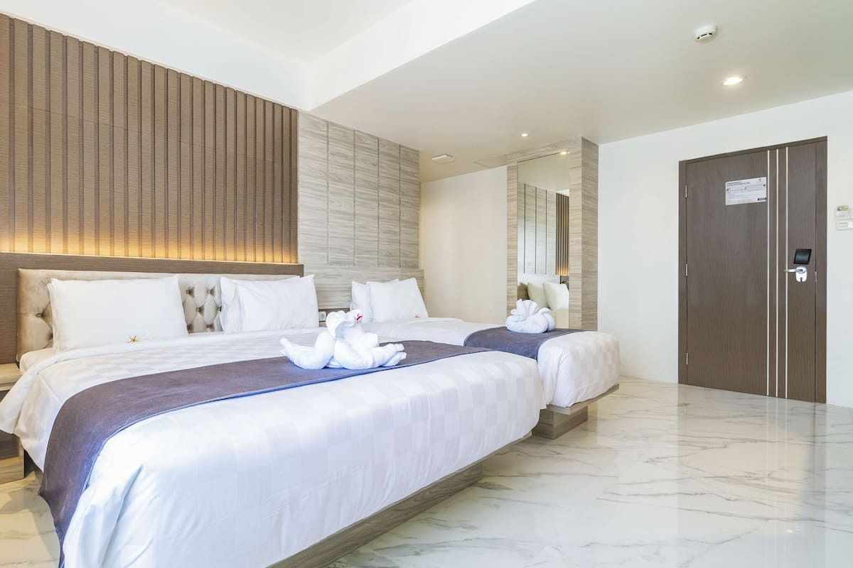 Ein modernes Hotelzimmer mit einem großen Bett, einem Holzkopfende, einem Marmorboden und einer Holztür.