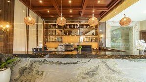Un espace bar doté de comptoirs en marbre, de luminaires sphériques suspendus et d  ’une variété de bouteilles et de verres disposés sur des étagères.