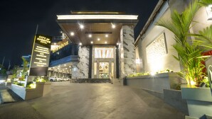 L’entrée d’un hôtel, avec une enseigne indiquant les équipements et services proposés, notamment un bar sur le toit, un centre de remise en forme et une piscine.
