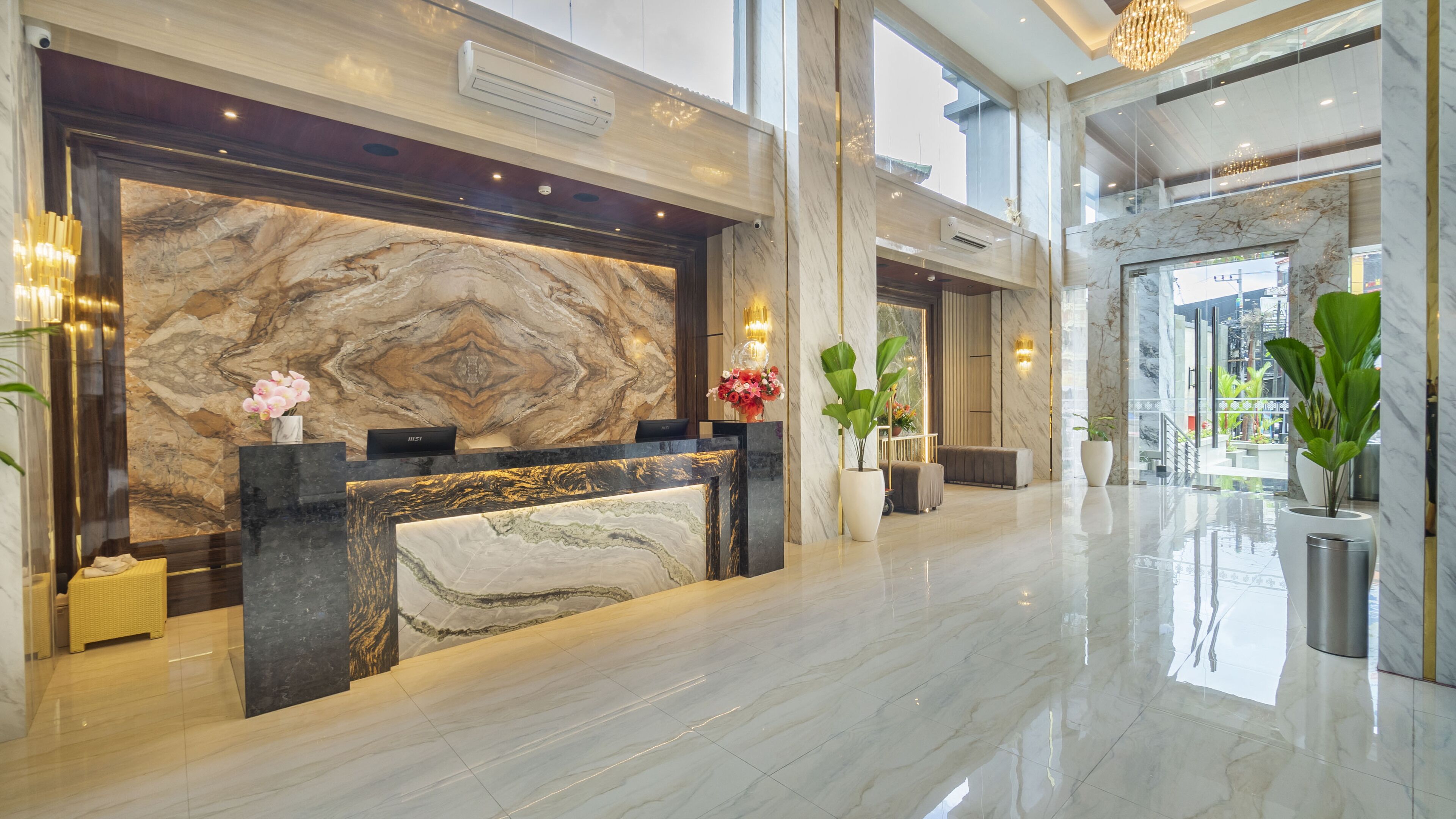 A modern reception area with a marble reception desk, potted plants, and a large window providing a view of the cityscape.
