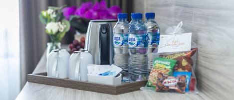 A tray with water bottles, a coffee maker, and a bag of snacks on a hotel room table.