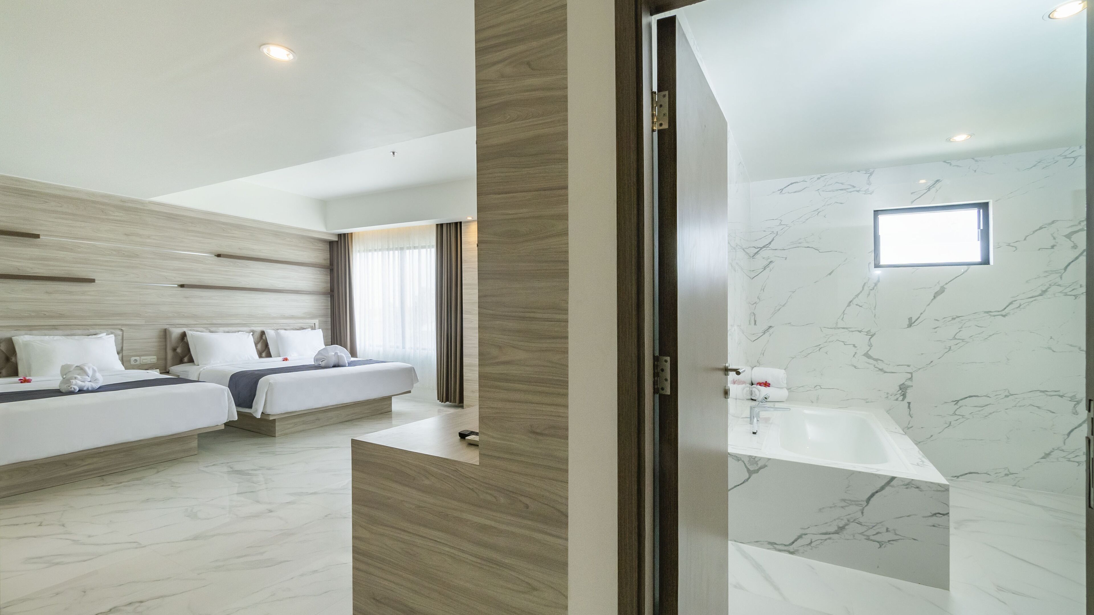 Una habitación de hotel moderna con dos camas, un ventanal grande y un baño de mármol.