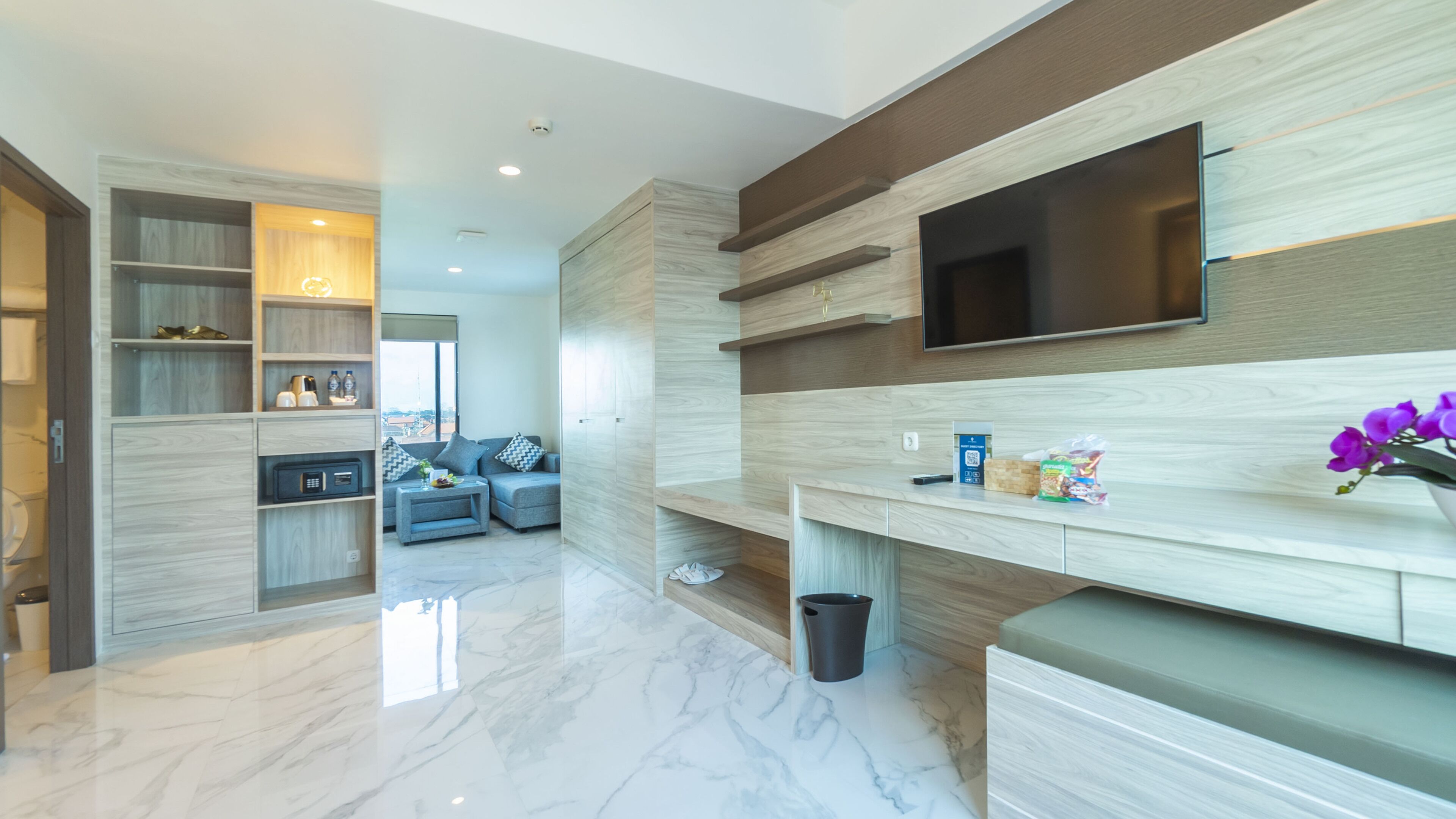 A modern kitchen with a built-in TV, marble flooring, and wooden cabinetry.
