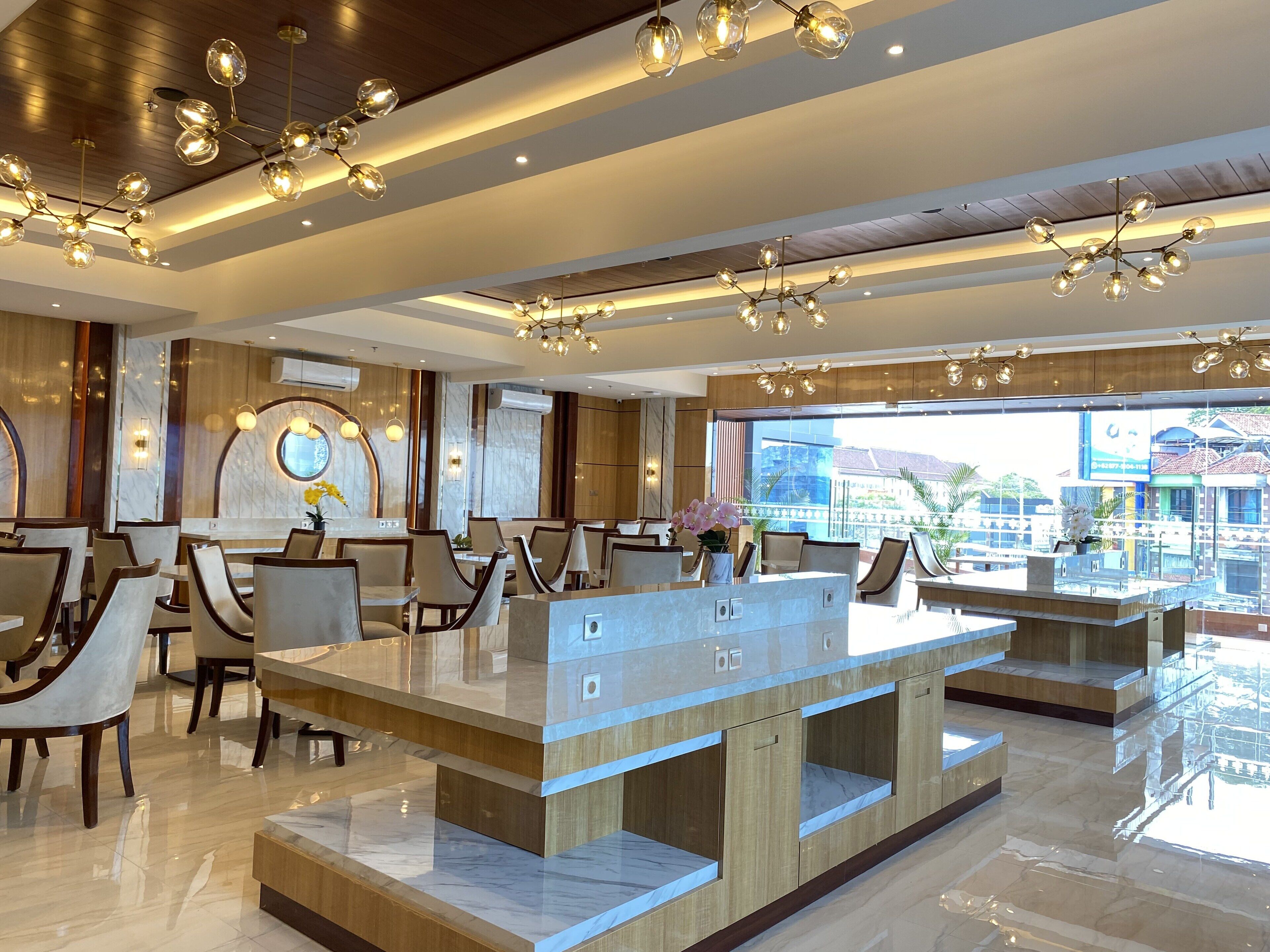 A modern hotel lobby with marble flooring, a central reception desk, and contemporary lighting fixtures.