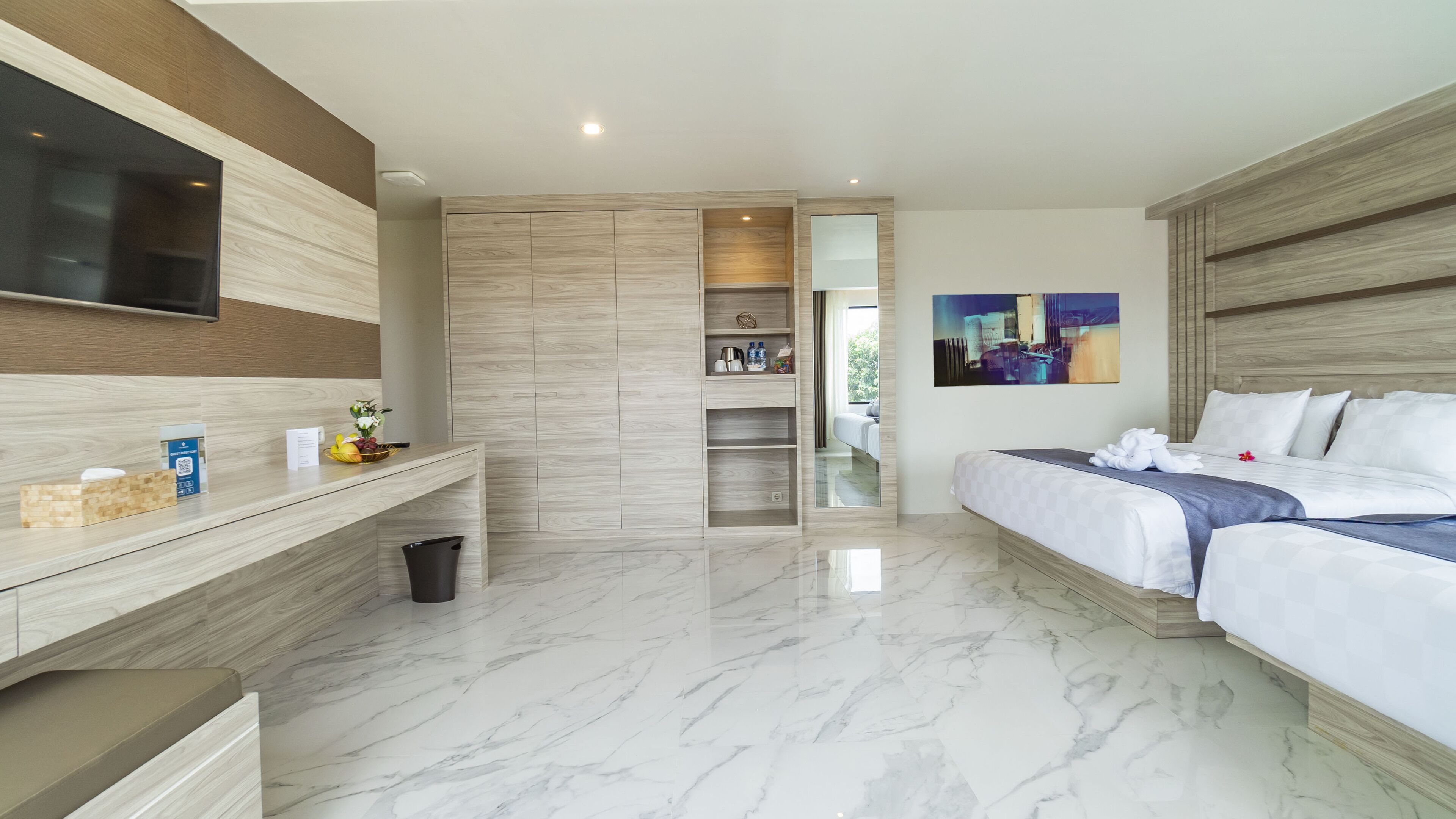 A modern hotel room with a large bed, a TV mounted on the wall, a wooden wardrobe, and a marble floor.