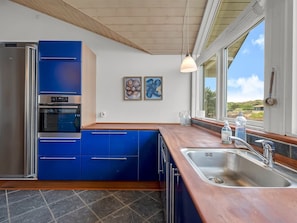 Una cocina moderna con armarios azules, un lavamanos de acero inoxidable y una obra de arte en la pared.