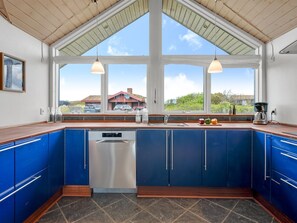 A kitchen with blue cabinets, a dishwasher, and a coffee maker. - "Thrugils" - 500m from the sea by Interhome (Henne)