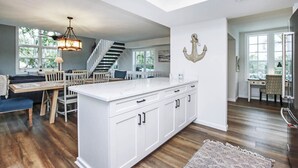 A modern kitchen with a central island, white cabinetry, and a staircase leading to another level. - Snook Away - Six bedroom bay front home nicely updated (Captiva)