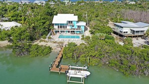 A coastal property with a large house, a swimming pool, and a dock extending into the water. - Snook Away - Six bedroom bay front home nicely updated (Captiva)