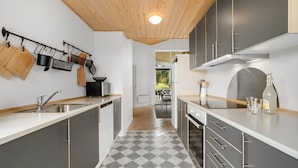 Una cucina moderna con mobili grigi, un pavimento a scacchi e un soffitto in legno.