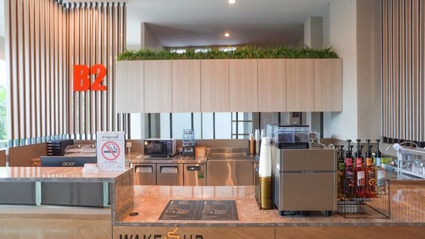A modern hotel reception area with a coffee machine, a no smoking sign, and a counter with a menu. - B2 Suan Luang Rama 9 Srinakarin 42 Boutique & Budget Hotel (Bangkok)