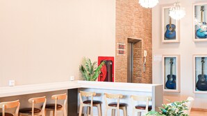 A reception area with a white counter, wooden chairs, a red safe, and framed guitars on the wall. - B2 Suan Luang Rama 9 Srinakarin 42 Boutique & Budget Hotel (Bangkok)