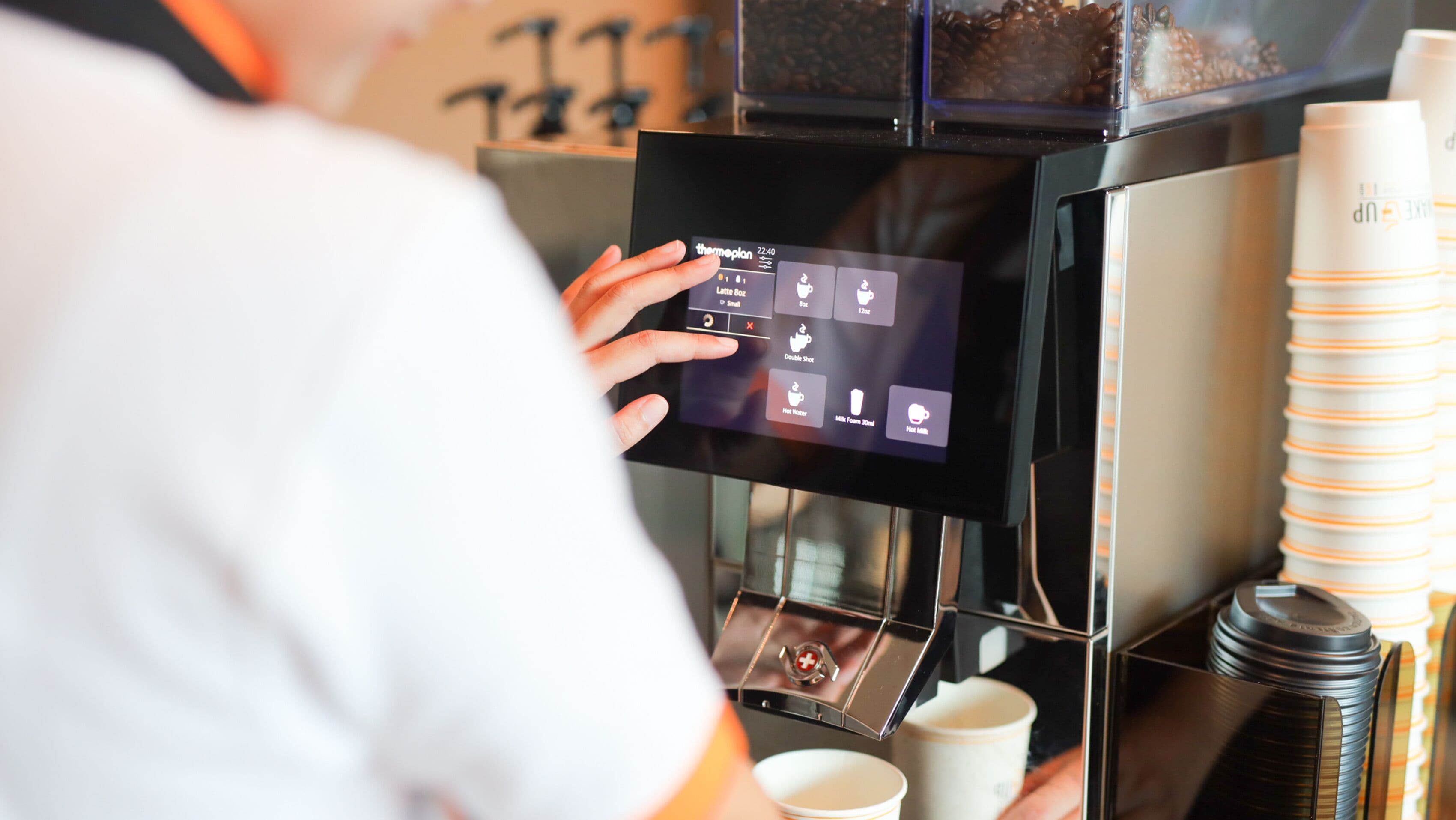 A person interacting with a coffee machine's touchscreen interface.