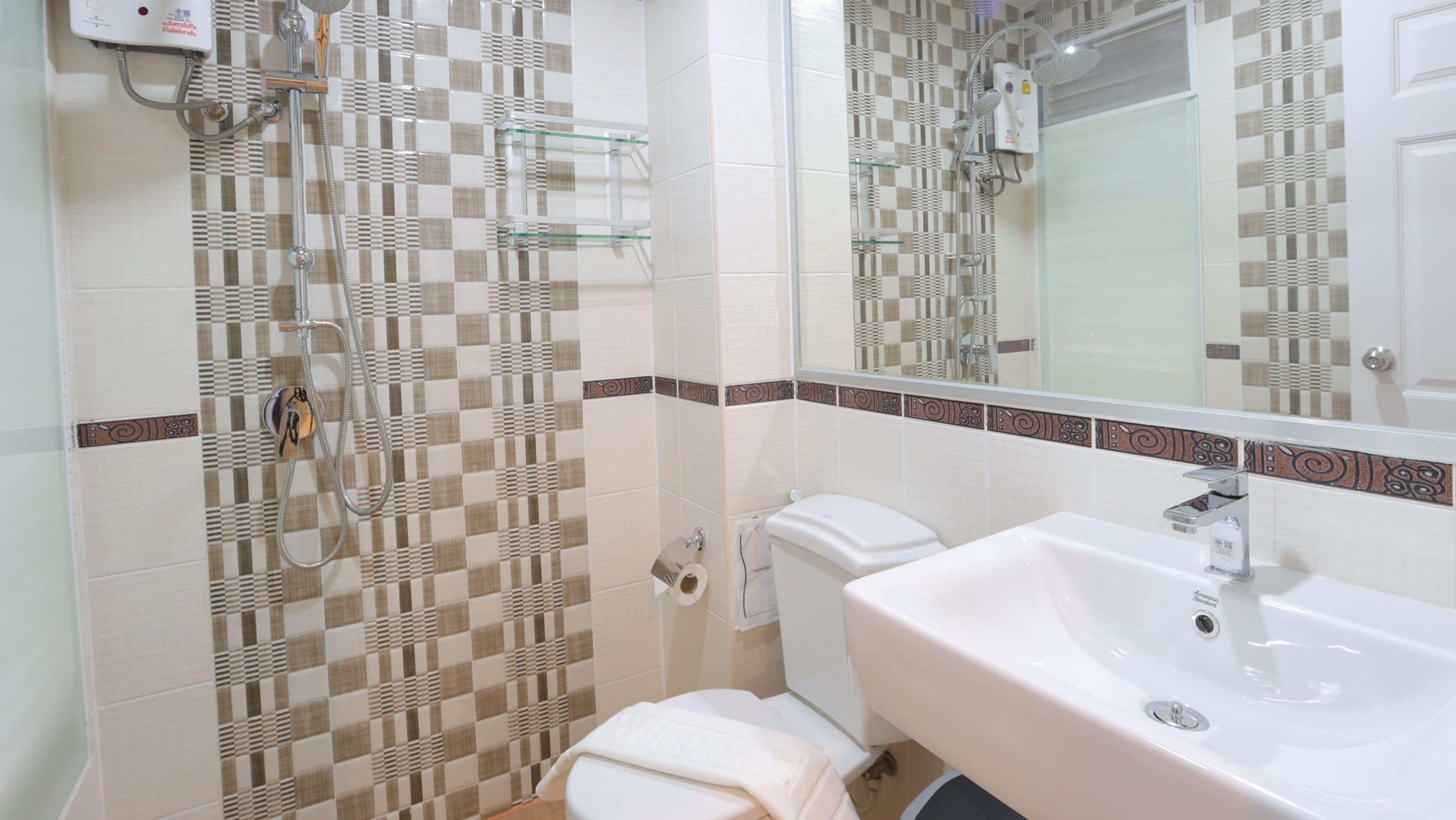 A bathroom with a checkered tile wall, a toilet, a sink, and a shower with a glass enclosure.