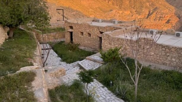 A stone pathway leading to a rustic building with a stone roof, surrounded by a mountainous landscape. - Matan Rural Lodge (At-Tafilah)