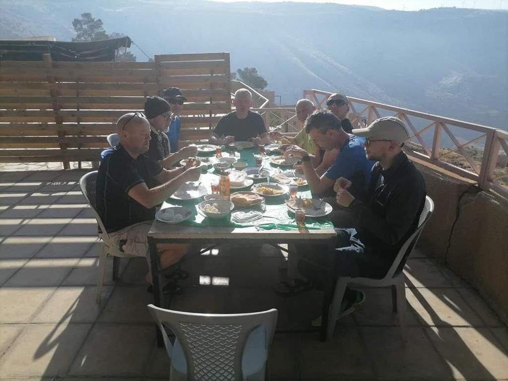 A group of people dining at an outdoor table with a scenic mountain view.