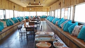 A long dining hall with wooden walls and benches, lined with various food dishes. - Matan Rural Lodge (At-Tafilah)