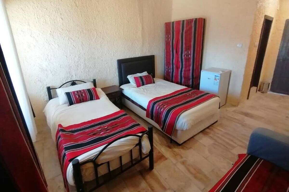 Una habitación con dos camas, cada una con una manta a rayas, un escritorio pequeño y un armario.