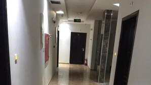 A corridor with tiled flooring, a fire alarm on the left, and a door at the end. - Kol Alayam Hotel (Makkah)