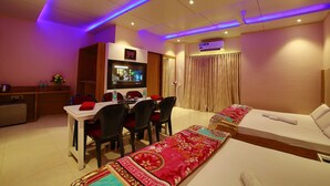 Una habitación de hotel con una cama, un escritorio con sillas, un televisor y una zona de comedor.