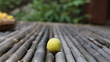 A close-up of a yellow ball on a bamboo mat with a blurred green background.