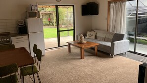 A cozy living room with a sofa, a wooden coffee table, and a kitchen area with a refrigerator and stove.