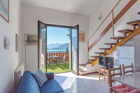 A living room with a sofa, a TV on a stand, a dining table, and a staircase. - Co.ri. Apartments (Menaggio)
