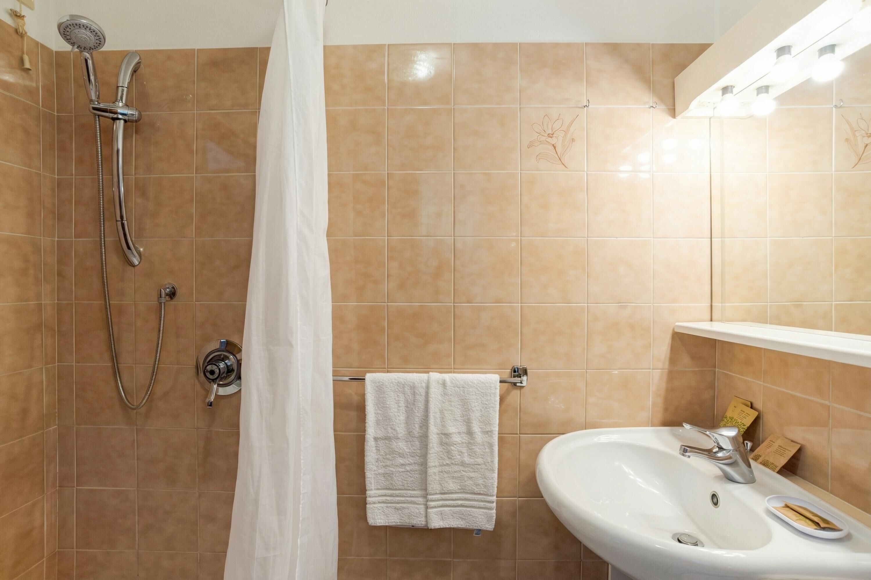 A bathroom with a shower, a sink, and a towel rack.