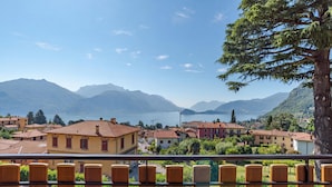 A coastal town with terracotta-roofed buildings, a clear blue sky, and a lake in the background. - Co.ri. Apartments (Menaggio)