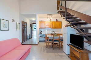 A modern kitchen with wooden cabinets, a dining table, and a TV on a stand. - Co.ri. Apartments (Menaggio)