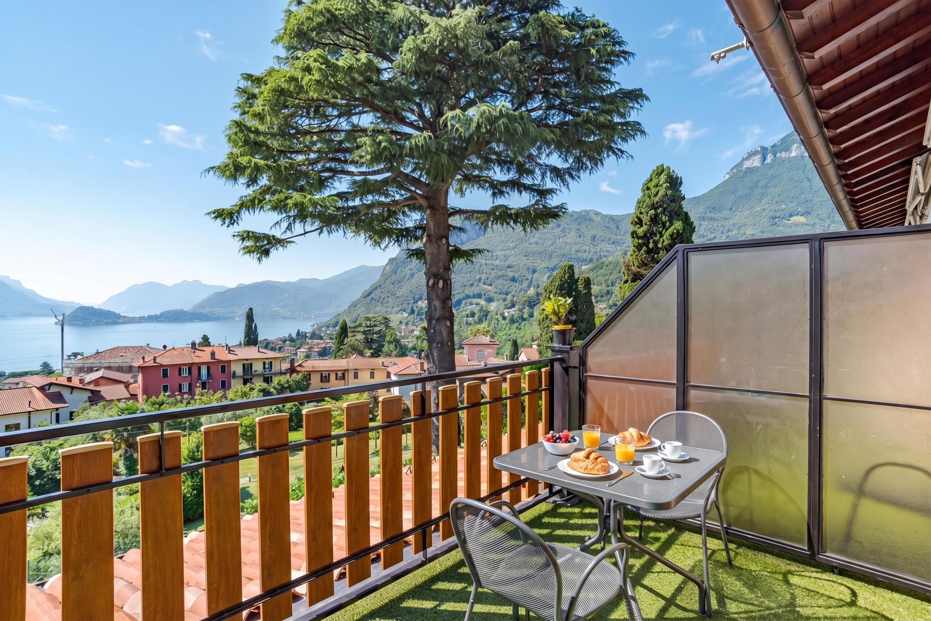 A balcony with a table set for breakfast, a view of a mountain, and a lake.